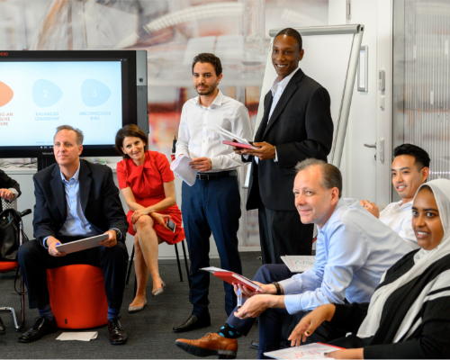 فريق يضم مجموعة متنوعة من موظفي Henkel يجلسون معًا في ورشة عمل وينظرون إلى المتحدّث