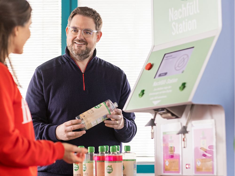A Henkel employee stands next to a refill station of the beauty brand Love Nature.