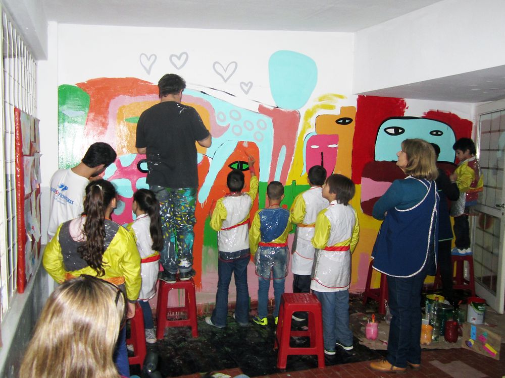Milo Lockett painting a mural with students.