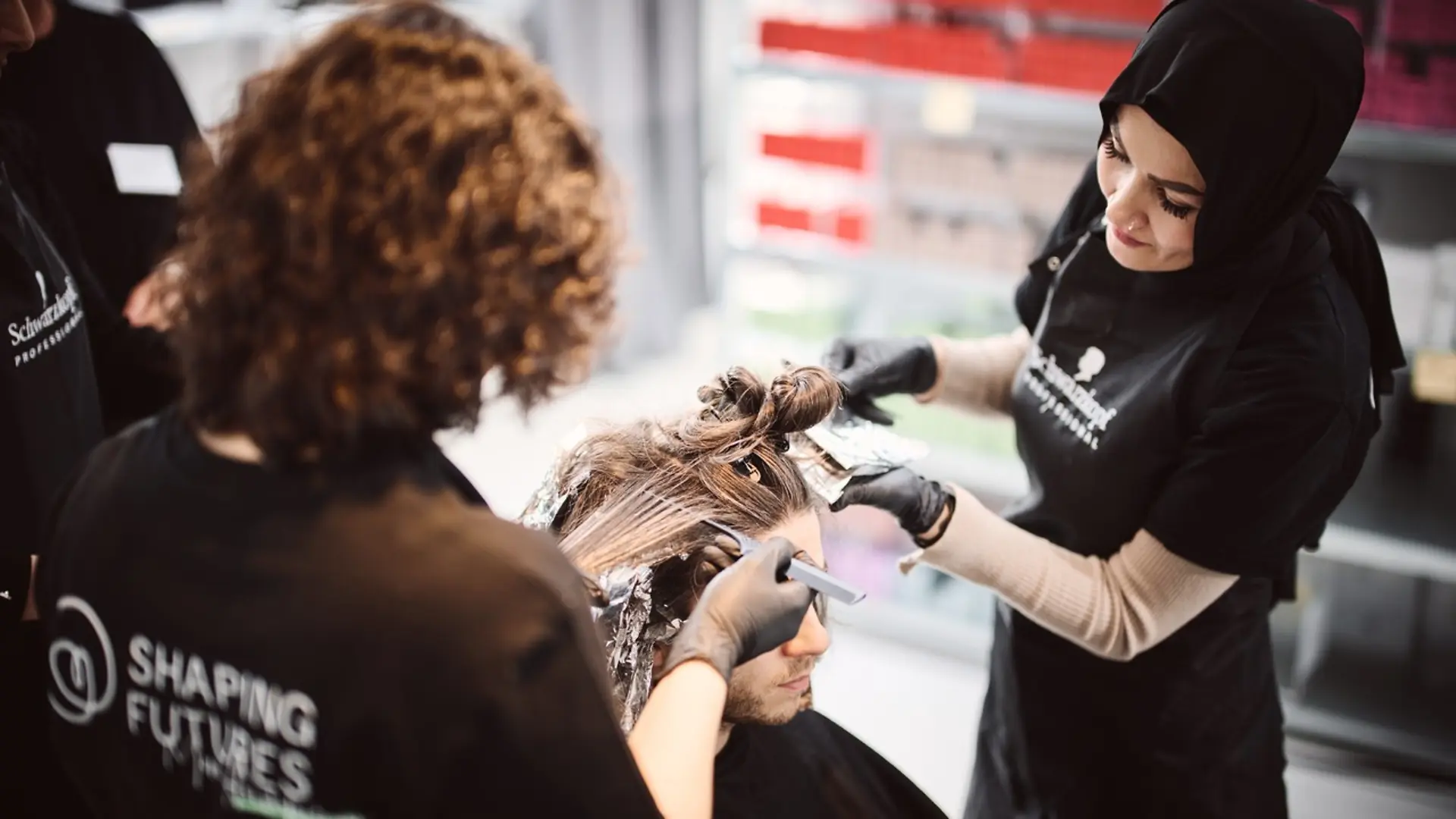 Two hairdressers working together in a professional salon for Shaping Futures